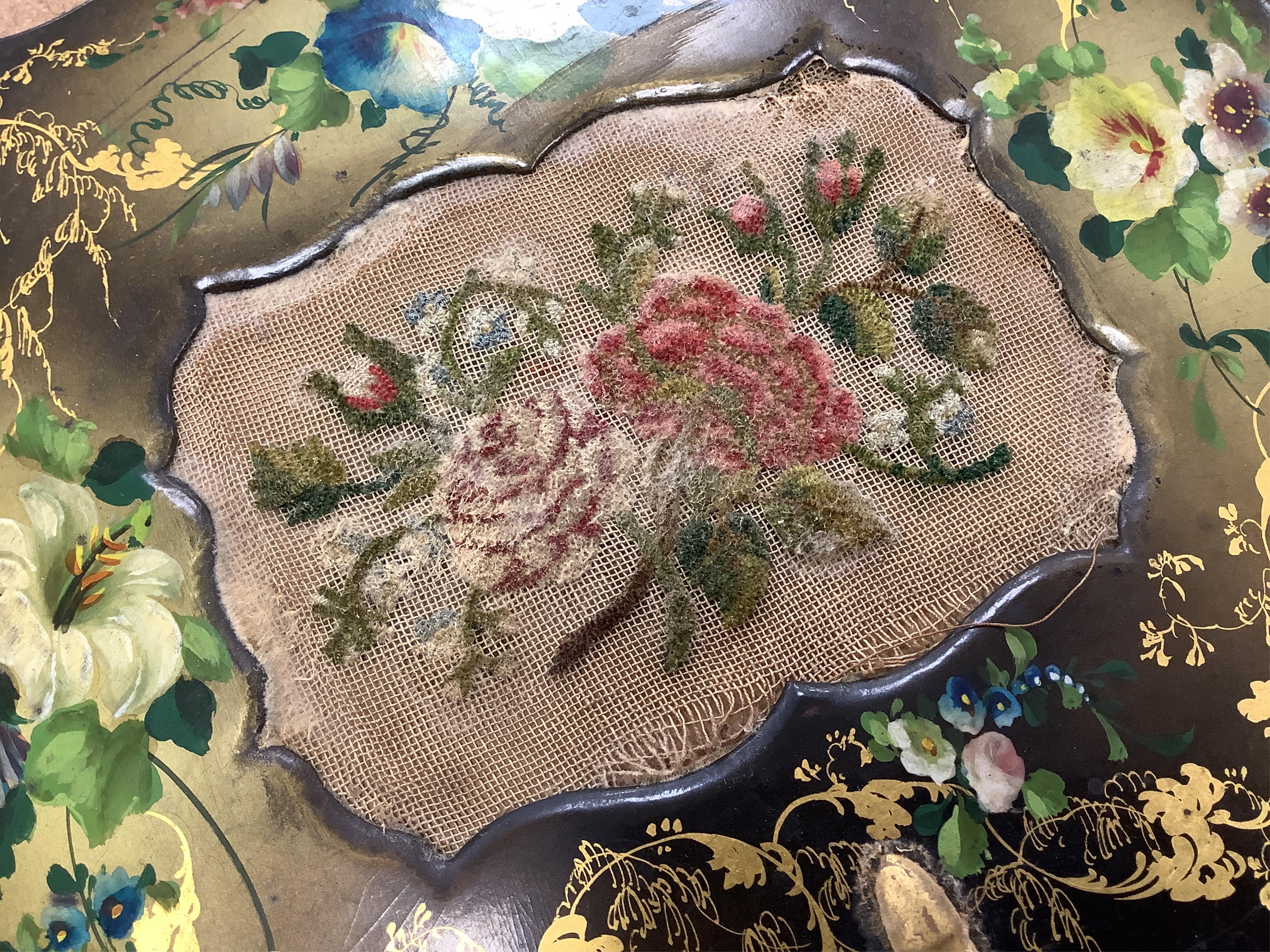 A pair of early Victorian papier maché hand screens, each with embroidered with cross stitched flowers, 41cm in length